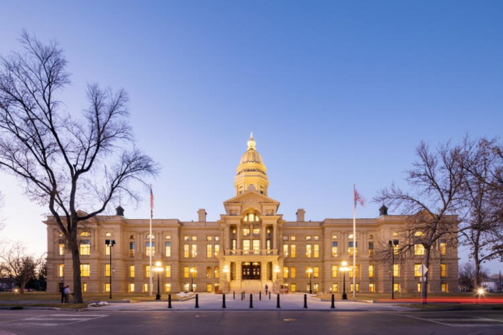 The Wyoming State Capitol in Cheyenne at dusk, its gold dome lit against a blue sky